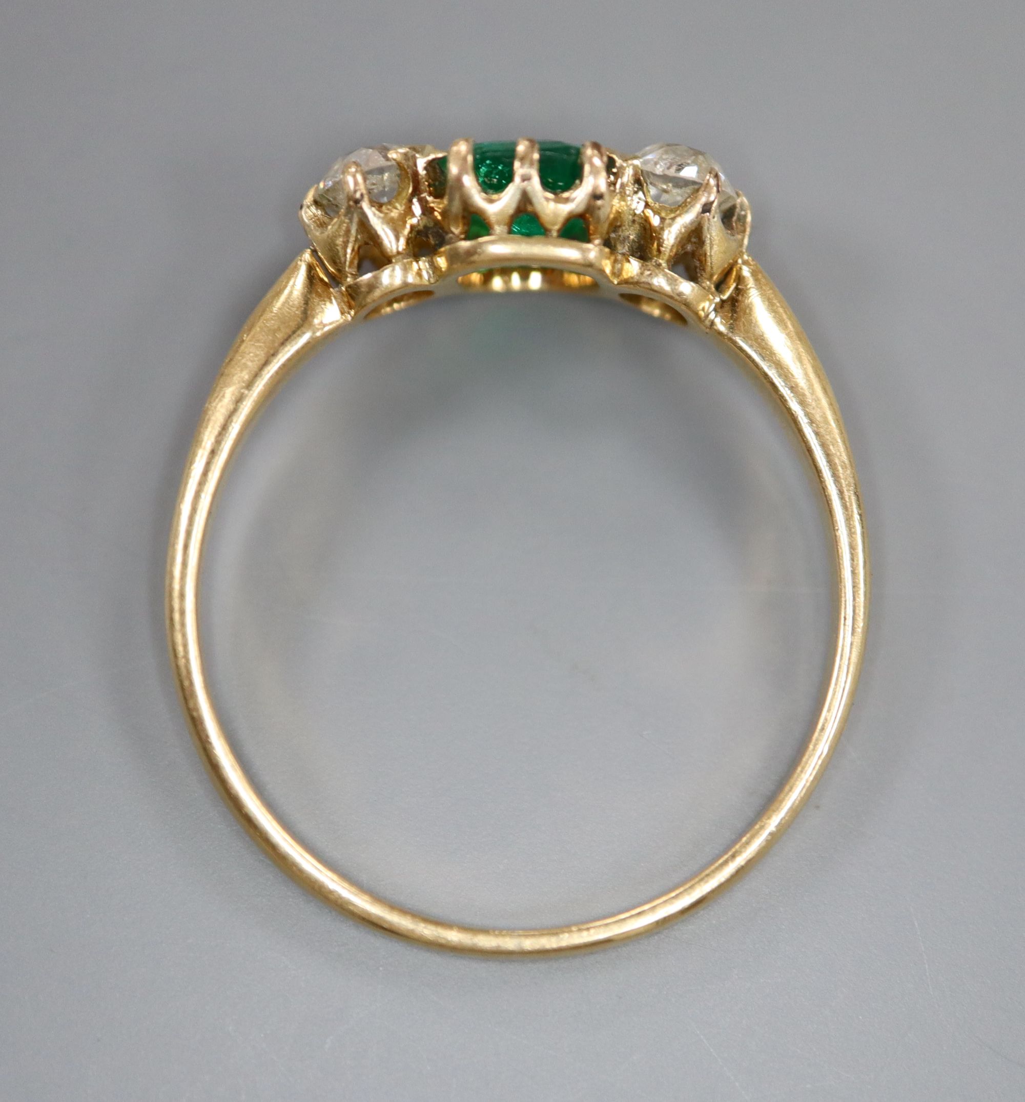 A yellow metal, emerald and diamond three stone ring, size Q, gross 2.3 grams.